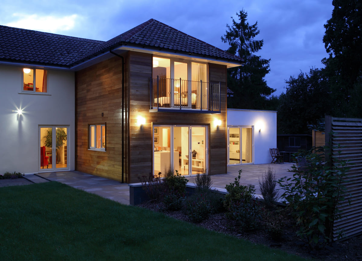 Two-story home at blue hour with warm lit rooms